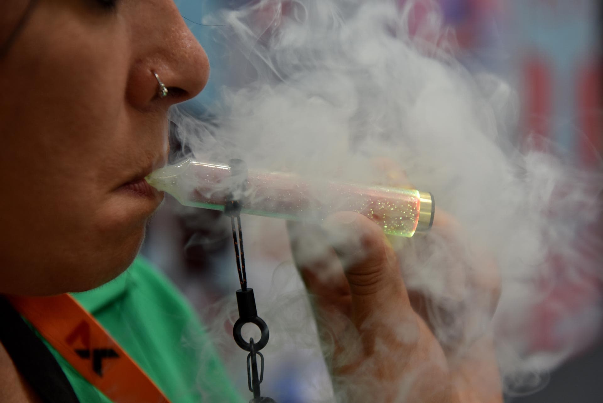 An exhibitor vapes on a McKesse glowing disposable e-cigarette during a Vaper Expo in Birmingham, England.